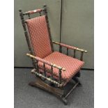 An early 20th century rocking chair with turned supports and arms, red floral fabric upholstery,