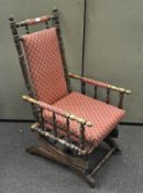 An early 20th century rocking chair with turned supports and arms, red floral fabric upholstery,