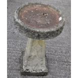 A stone bird bath with circular top