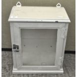 A white glazed metal wall cabinet, with glass windows to three of the sides and a twist lock,
