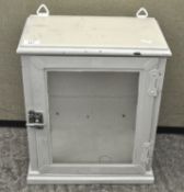 A white glazed metal wall cabinet, with glass windows to three of the sides and a twist lock,