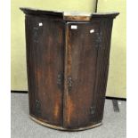A 19th century oak bow fronted, two door corner cabinet, with brass hinges and lock,