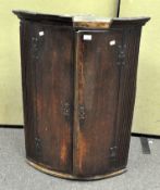 A 19th century oak bow fronted, two door corner cabinet, with brass hinges and lock,