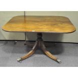 A 19th century mahogany dining table, the quad flowing legs with brass lion paw feet,