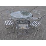 A modern circular garden table with glass top and six chairs, with coloured floral decoration,