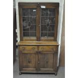 An early 20th century oak glazed bookcase over a two door cupboard with two frieze drawers,