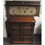 A 20th century cupboard with carved details to the front and metal handles and fastenings,