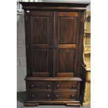 A modern mahogany wardrobe, with a pair of panelled doors over four drawers,