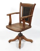 An oak captain's chair, with a black leatherette back rest, sold seat and quadripartite base,