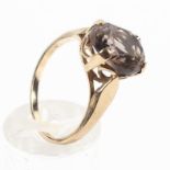 A yellow metal ring set with an oval cut smoky quartz measuring approximately 12mm x 10mm.