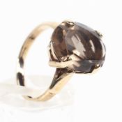 A yellow metal ring. Set with an oval cut smoky quartz measuring approximately 14.0mm x 10.0mm.