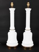 A pair of white glass lamp bases, of column form on a bell shaped base,