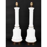 A pair of white glass lamp bases, of column form on a bell shaped base,