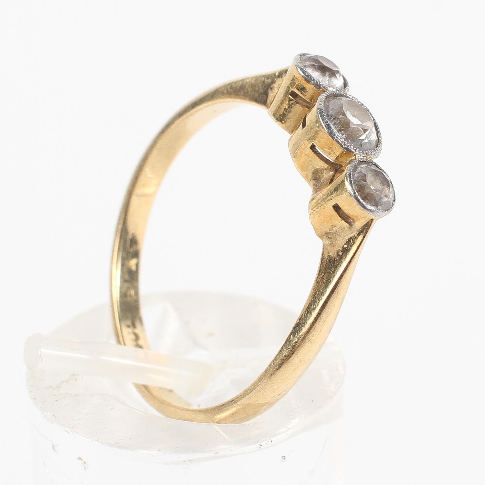 A yellow metal three stone ring set with three graduated round cut white stones;