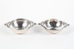 A pair of continental silver porringers, of hammered form, twin handled,