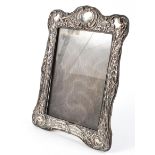 An Edwardian silver mounted photo frame, adorned with embossed scrolling foliate borders,