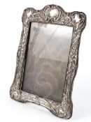 An Edwardian silver mounted photo frame, adorned with embossed scrolling foliate borders,