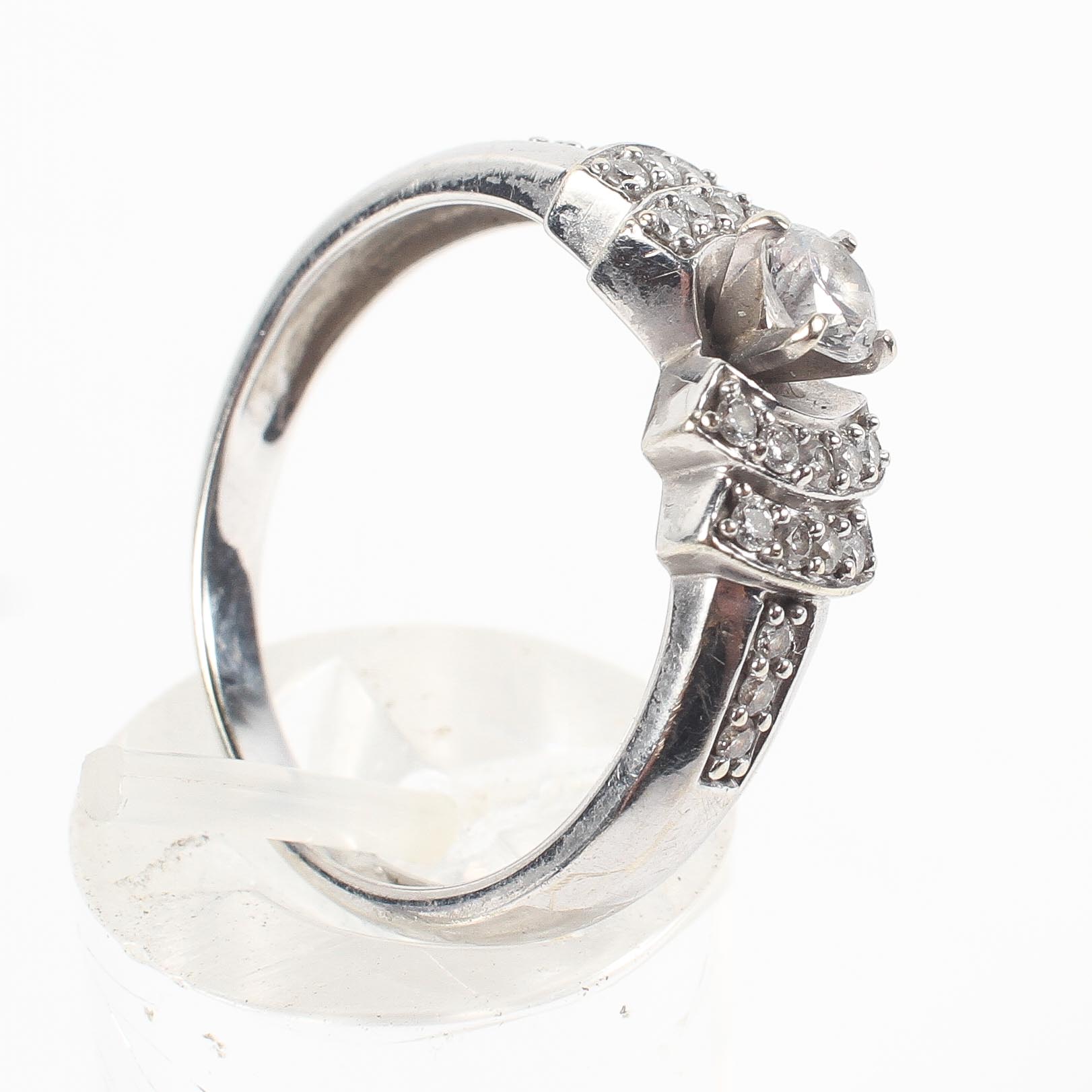 A white metal ring principally set with a round brilliant cut diamond estimated to weigh 0.25cts.