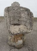 A cast stone garden seat on a scrolling base,