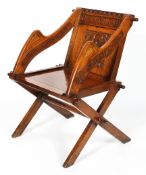 An oak Glastonbury chair, carved with roundel and script, raised on cruciform base,