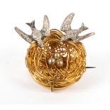 A novelty gilt and white metal brooch in the form of a bird's nest with two swallows