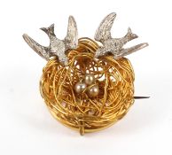 A novelty gilt and white metal brooch in the form of a bird's nest with two swallows