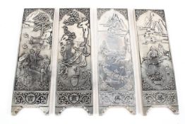 A set of four Chinese white metal plaques, each cast with figures in a landscape,