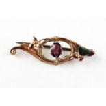 A yellow metal bar brooch set with an oval cut rhodolite garnet. Stamped 9ct