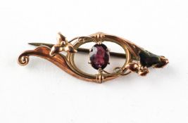 A yellow metal bar brooch set with an oval cut rhodolite garnet. Stamped 9ct