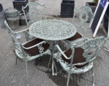 A garden patio set in green painted metal cast with fruiting garlands,