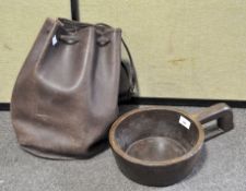 A leather duffel bag containing a single handled wooden bowl