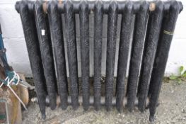 A vintage black painted heavy cast iron radiator, cast with scrolls, raised pattern,