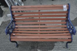 A garden bench with slatted wooden back and seat and cast iron scroll lion arm rests,