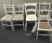 Five white painted wooden chairs, with wicker seats, four with floral seat cushions,
