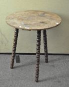 A small wooden table, with circular top, on three twist supports,