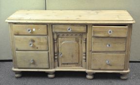 A Victorian stripped pine chest of drawers, three drawers on either side with a door to the centre,