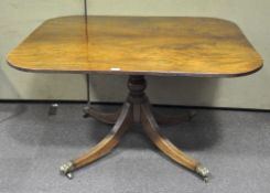 A 19th century mahogany dining table, the quad flowing legs with brass lion paw feet,