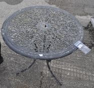 A black painted aluminium circular garden table cast with scrolling leaves,