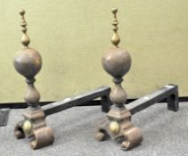 A pair of iron and brass fire dogs, topped with finials,