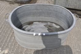 A large galvanized tin bath of oval form with twin handles,