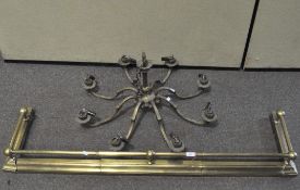 An eight light brass chandelier and a brass fender with ball finials,