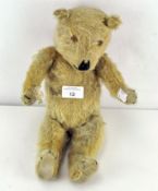 A 20th century teddy bear with golden fur, pronounced snout, stitched nose, mouth and claws,