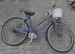 A vintage blue ladies Raleigh bicycle with a basket,