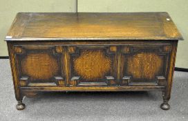 An antique oak coffer with three panel front, the front carved with lozenges, on raised feet,