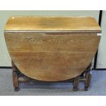 An oak folding gate leg dining table of oval form, with turned baluster legs,