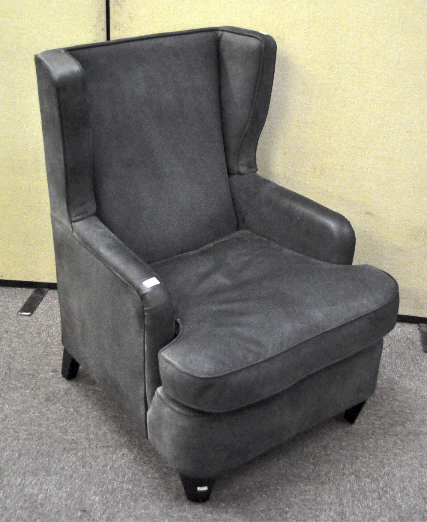 A contemporary black upholstered wingback armchair, upholstered in black suedette,