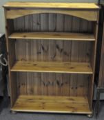 A contemporary pine bookcase, with two shelves, raised on turned supports,