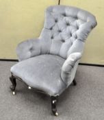 A Victorian button back blue velvet upholstered armchair, on casters,