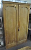 A Victorian stripped pine two door wardrobe with hat shelf above two hanging/shelving spaces,