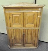 A Victorian pine corner cabinet with three fluted shelves behind double doors,